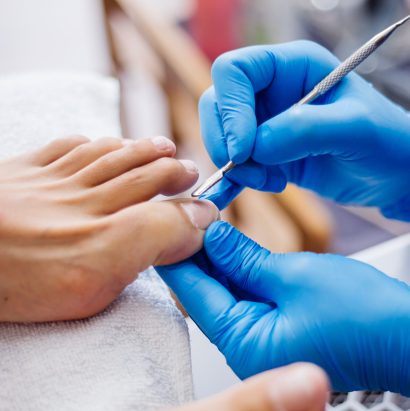 proceso-pedicura-pedicura-salon-casa-tratamiento-cuidado-pies-proceso-pedicura-profesional-maestro-guantes-azules-hace-pedicura